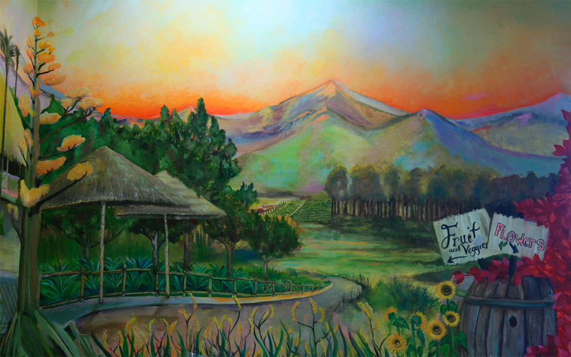 Finished Trader Joe's mural, sunset mountains, thatched hut, sunflowers, and hand-painted 'Fruit and Veggies / Flowers' signs.